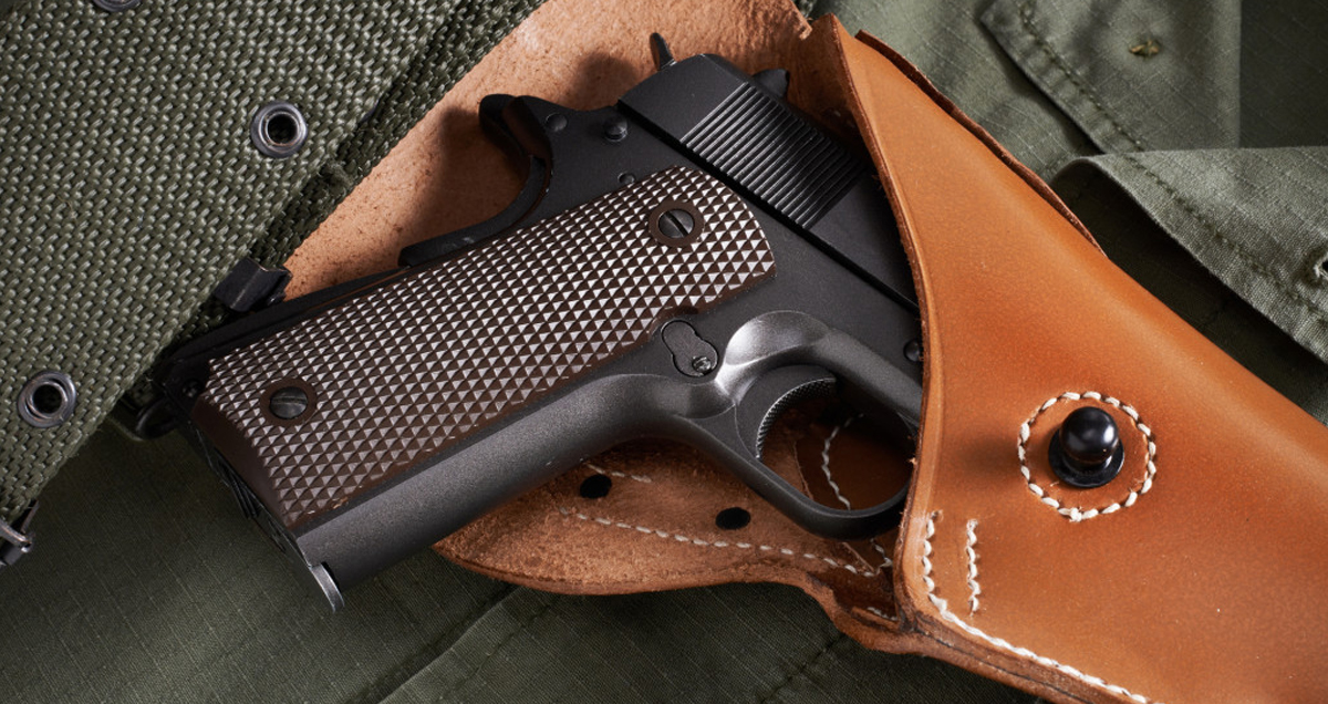 Colt pistol in holster and belt lie on military jacket gun safety